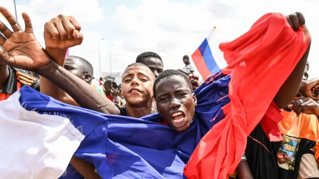 a nigerien protester waving a russian flag outside a military base