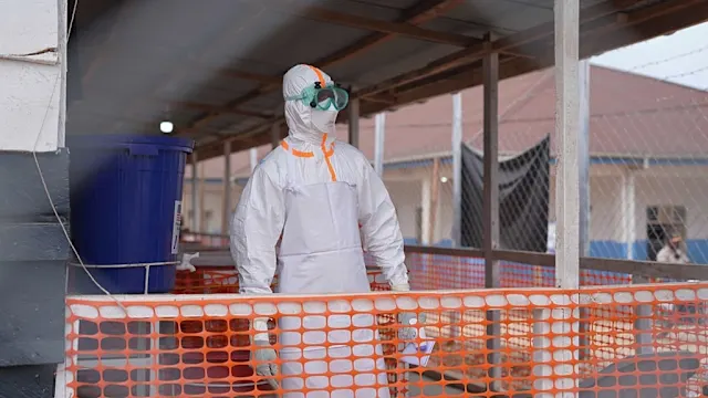 Healthcare workers in protective gear attending to patients in a medical facility